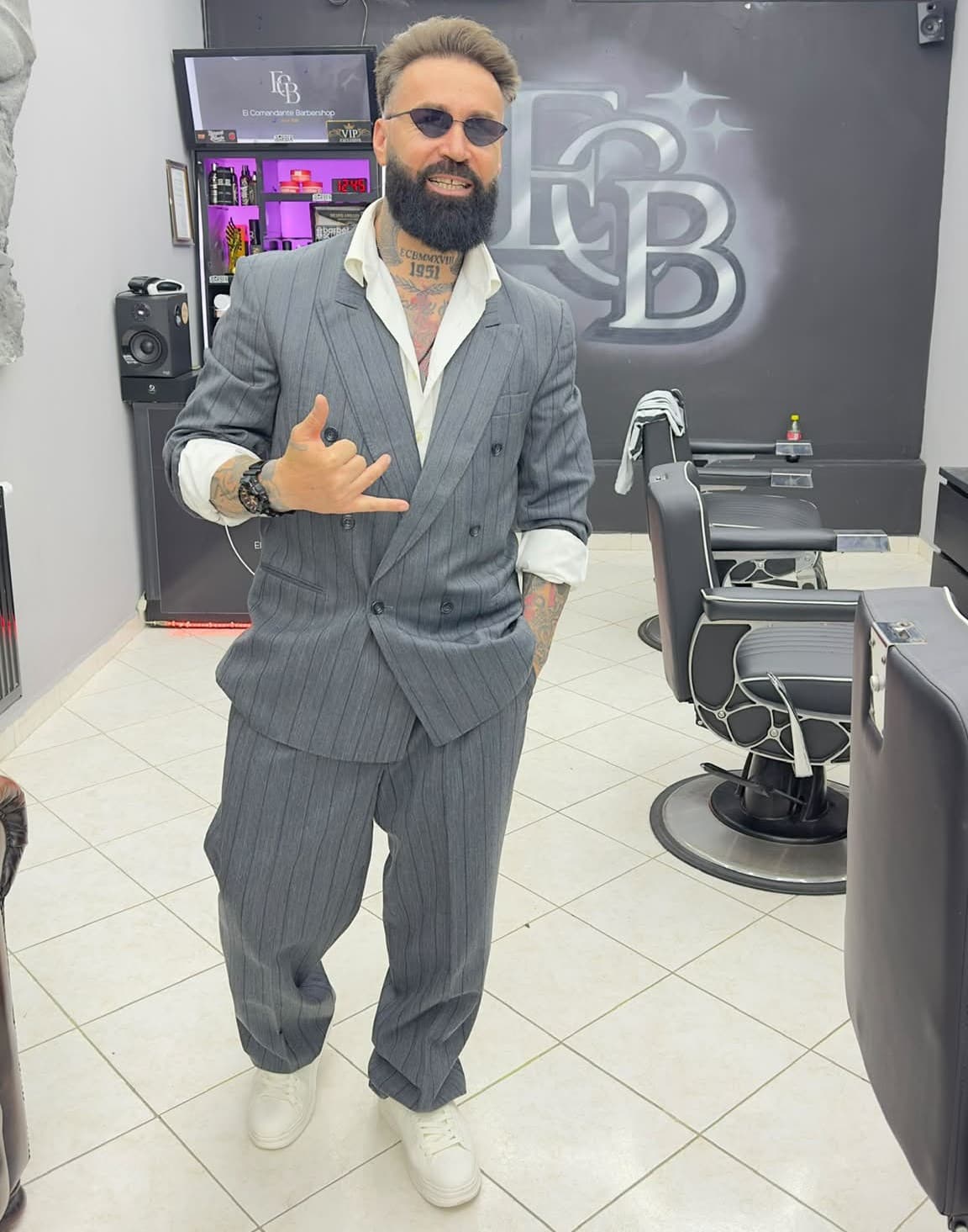 Juliano — owner și maestru barber al El Comandante Barbershop, în costum alb cu cască de motocicletă, interior salon