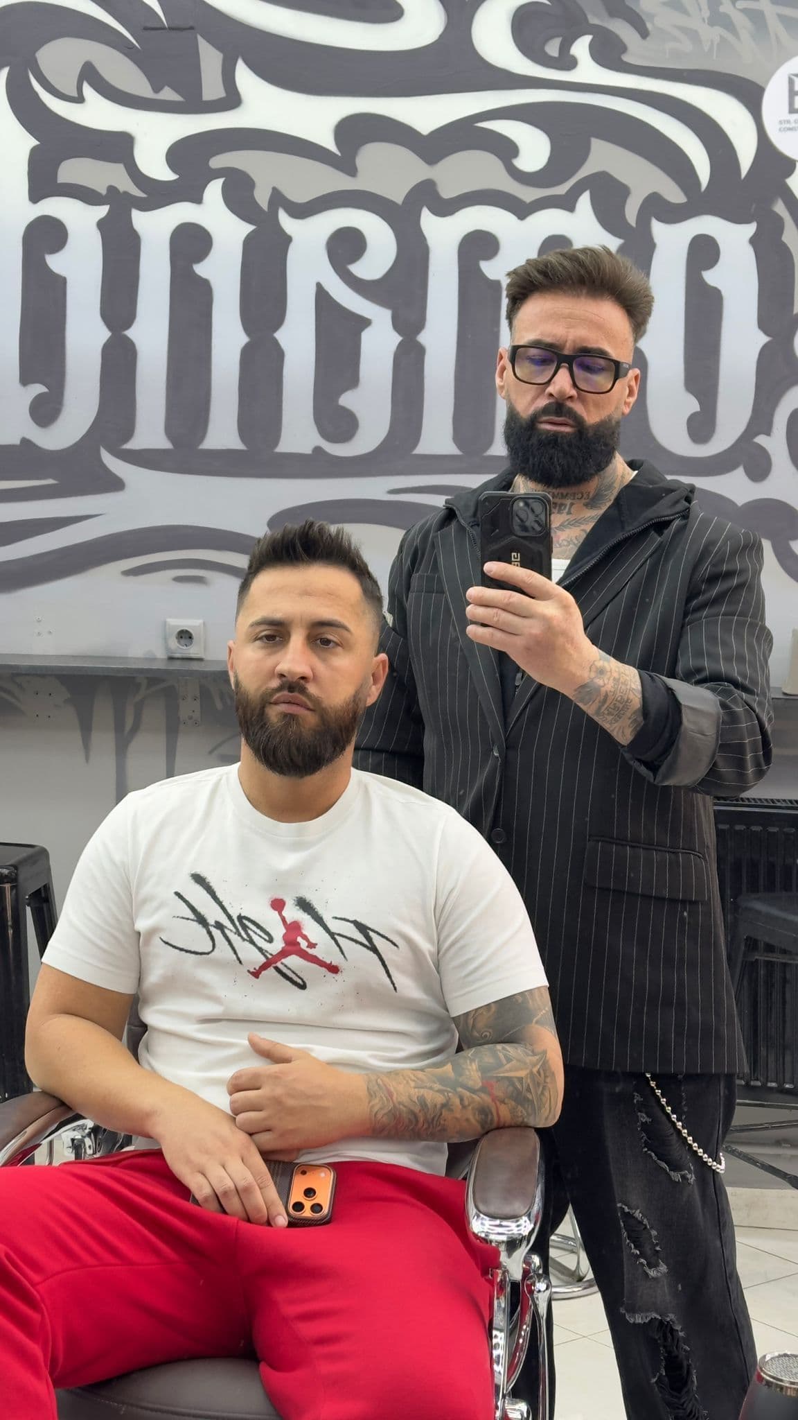 Juliano și client satisfăcut după tunsoare impecabilă, muralul Comandante în fundal