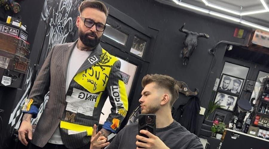 Client în scaunul de frizer se fotografiază în oglindă — interiorul elegant al salonului